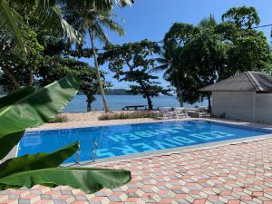 a swimming pool with a view of the water at White Sands Beach Resort Lembeh in Bitung
