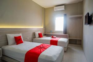 a hotel room with two beds with red pillows at RedDoorz Syariah near PRPP Semarang in Kalibanteng-lor