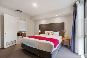 a bedroom with a large bed with a red blanket at Knox International Hotel and Apartments in Wantirna