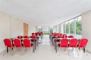 une salle de conférence avec des chaises et des tables rouges dans l'établissement Ibis Budget Semarang Tendean - CHSE Certified, à Semarang