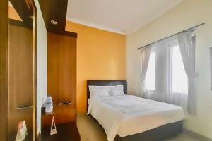 a bedroom with a white bed and a window at RedDoorz Syariah Plus near Cirebon Super Block Mall 2 in Cirebon