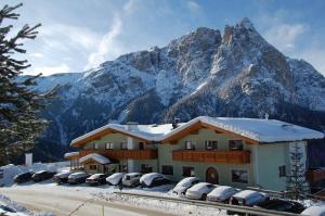 a building with cars parked in front of a mountain at Hotel Gstatsch in Alpe di Siusi