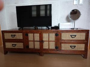 a television on top of a wooden cabinet with drawers at Mirinae Hanok Tradiational House in Gwangyang