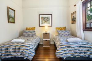 two twin beds in a room with a lamp between them at Kembali on Massinger Street in Byron Bay