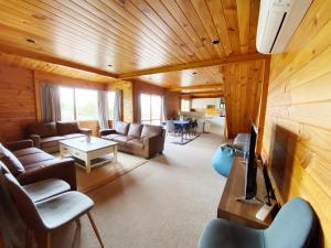 ein Wohnzimmer mit einem Sofa und einem TV in der Unterkunft Lake view family Lodge up tp 14 people in Rotorua