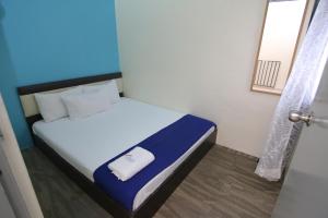 Un pequeño dormitorio con una cama con sábanas azules y blancas. en Homestay Hj Esmon 3 UTHM Parit Raja, en Parit Raja