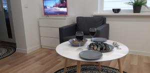 a white table with two glasses of wine and cookies at Butas Senamiestyje Vytauto 7-4 in Rokiškis