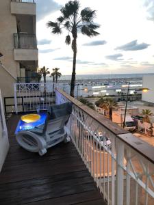 einen Stuhl auf einem Balkon mit einer Palme in der Unterkunft Sweet li in Aschkelon