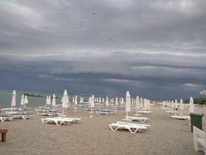 - un bouquet de chaises longues et de parasols sur une plage dans l'établissement Belchevi Apartments, à Bourgas