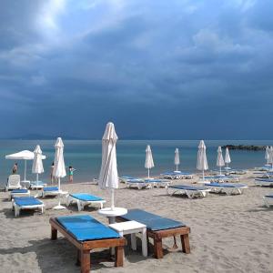 a beach with chairs and tables and white umbrellas at Belchevi Apartments in Burgas City