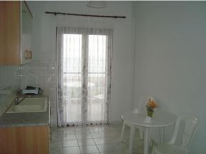 biała kuchnia ze stołem i oknem w obiekcie Yianna Studios & Apartments w mieście Gerakini