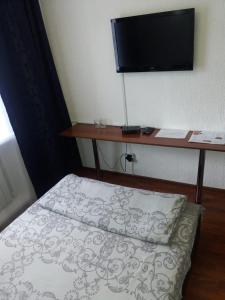um quarto com uma cama e uma secretária com uma televisão em Nuri Hotel Стадион em Karaganda