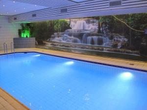 a large swimming pool with a waterfall in the background at Fletcher Hotel-Restaurant Nieuwegein-Utrecht in Nieuwegein