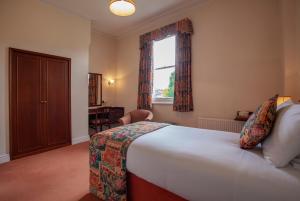 a bedroom with a bed and a window and a desk at Arundel House Hotel in Cambridge