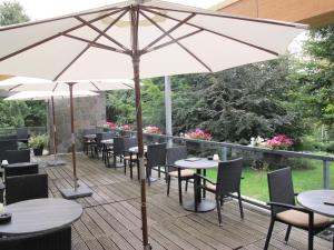 un patio con mesas, sillas y una sombrilla en Fletcher Wellness-Hotel Stadspark en Bergen op Zoom