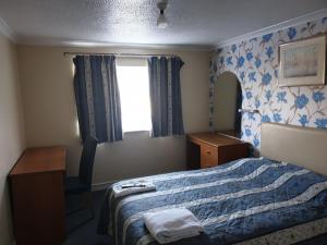 a bedroom with a bed and a desk and a window at Elmhurst Hotel in Reading