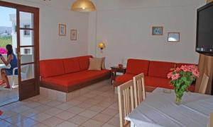 uma sala de estar com um sofá vermelho e uma mesa em John Mary Apartments em Gouves