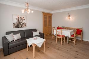 a living room with a black couch and a table at Appartement Erwin & Eleonore Hüttl - Top 1 in Neukirchen am Großvenediger