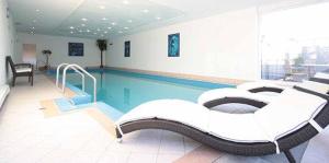 a swimming pool with two beds in a room at Naturhotel Am Sonnenhang in Oy-Mittelberg
