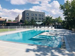 a swimming pool with chairs and a building in the background at Hotel Parque Real in Ciudad Real