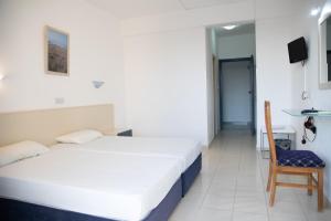a hotel room with two beds and a chair at West End Hotel in Peyia