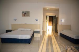 a hotel room with two beds and a hallway at West End Hotel in Peyia