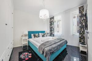 a white bedroom with a blue bed and a chandelier at Bursztynowe Osiedle Jantar, Sun & Snow in Jantar