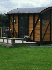 uma grande cabana de madeira com um alpendre e relva em Pen-Rhos luxury glamping "Cuckoo's Nest" em Llandrindod Wells