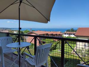un tavolo e delle sedie su un balcone con un ombrellone di Welcome Traveller CASA MARA a Lazise