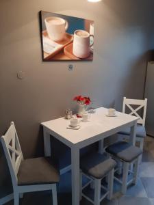 einen weißen Tisch mit Stühlen und ein Gemälde an der Wand in der Unterkunft Warszawska in Legionowo