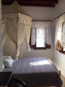 a bedroom with a bed with curtains and a window at Loukakia apartments in Patmos