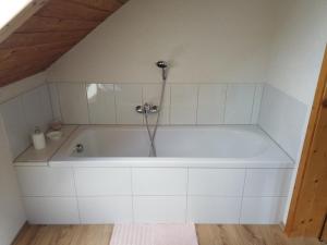 eine weiße Badewanne mit Dusche im Zimmer in der Unterkunft Ferienhaus Oma Hase in Mürzzuschlag