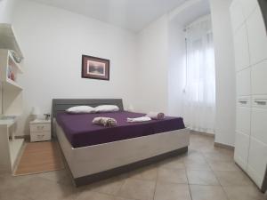 a bed in a white room with a purple mattress at Aquamare Apartment in Rijeka