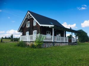 a brown house with a porch on a green field at Holidayhome Juksty in Mrągowo
