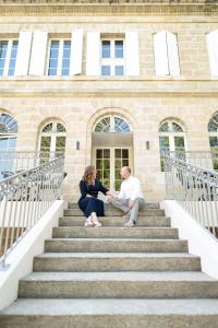 um homem e uma mulher sentados nas escadas de um edifício em Pavillon des Millésimes em Lussac