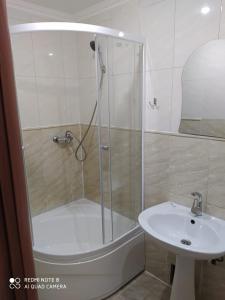 eine Dusche mit Glastür neben einem Waschbecken in der Unterkunft Nuri Hotel Стадион in Qaraghandy