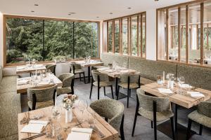 un restaurante con mesas, sillas y ventanas en Falkensteiner Hotel Antholz - Adults only en Anterselva di Mezzo