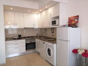 a kitchen with white cabinets and a white refrigerator at Armação de Pêra Praia Mar Sol in Armação de Pêra
