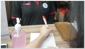 a person writing on a piece of paper with a pen at RedDoorz Plus near Teras Kota 3 in Tangerang