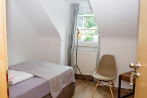 a bedroom with a bed and a chair and a window at Stadthotel Marburg in Marburg an der Lahn
