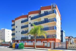 a tall building with a palm tree in front of it at Apartamentos en la playa Edimar II in Gandía
