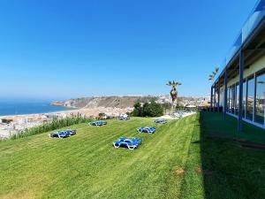 un campo de césped con coches estacionados en un lateral de un edificio en Miramar Hotel Spa & Apartments en Nazaré