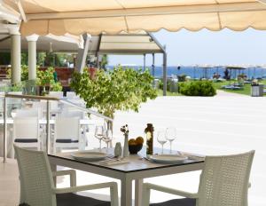 a dining table with chairs and an umbrella on a patio at Apollo Beach in Faliraki