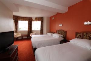 a hotel room with three beds and a flat screen tv at The Esplanade Hotel in Scarborough