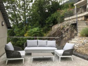 a patio with a couch and two chairs and a table at Rustico RESA: Brione sopra Minusio in Brione sopra Minusio
