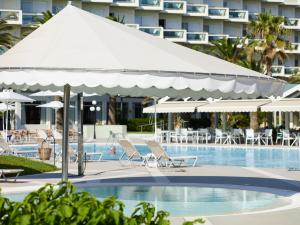 a pool with chairs and umbrellas next to a hotel at Apollo Beach in Faliraki