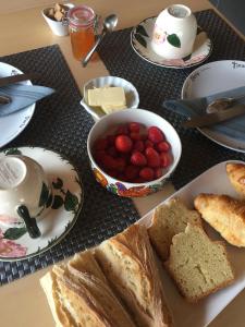 einen Tisch mit einem Teller Brot und einer Schale Erdbeeren in der Unterkunft La Ferme du Preneau in Challans