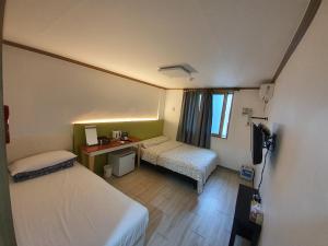 a small room with two beds and a desk at K Guesthouse in Gangneung