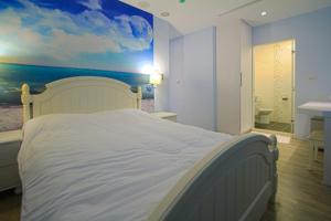 een slaapkamer met een wit bed en een schilderij aan de muur bij 澎湖寶島時尚別館 Bao Dao B&B in Hui-min-erh-ts'un