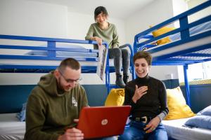 two men sitting on beds in a bedroom with a laptop at The Woodquay Hostel in Galway
